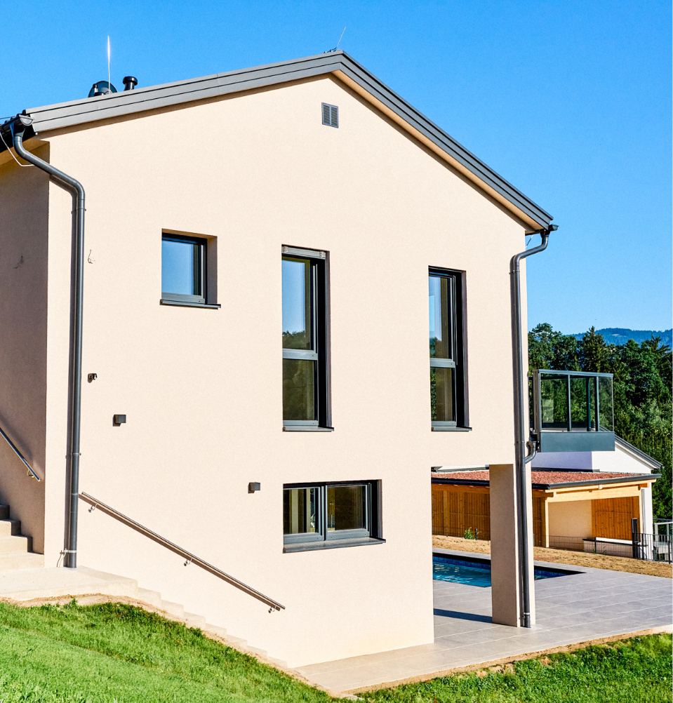 Außenansicht eines Einfamilienhauses mit Carport, Zaun und Grüneinfassung.