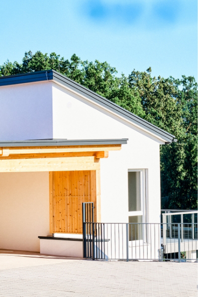 Detailansicht eines modernen Einfamilienhauses mit hölzerner Überdachung und Zaun.