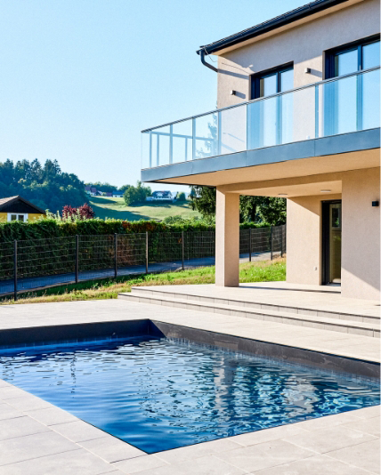 Terrasse mit rechteckigem Swimmingpool und Blick auf das angrenzende Wohnhaus.